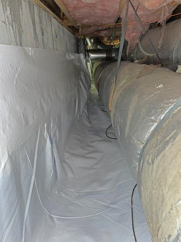 With the wet moldy fiberglass insulation removed from the walls, the CleanSpace vapor barrier is properly sealed up the walls, using pins and sealant at the top edge of the barrier to keep moisture from rising up into the space.