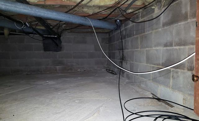 Looking at the back wall we can see an opening where pipes and wires pass through.  The foundational wall is located to the left of this picture.