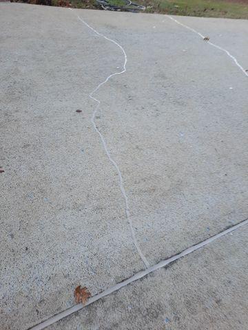 Cracked concrete driveway that has been repaired.