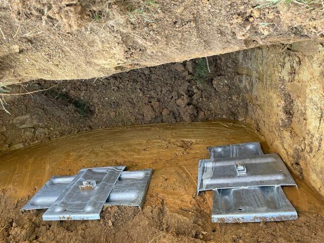 A close-up shot shows two Geo Locks securely gripping the soil surrounding the foundation.