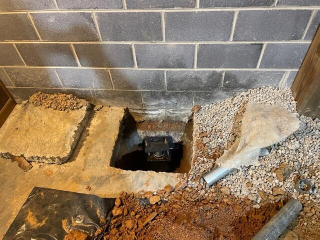 A close-up of a portion of the basement, showing a Push Pier installed under the home footing.