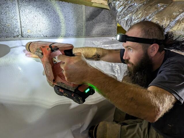 A close-up of one of our crew members securing the CleanSpace liner on the crawlspace walls.