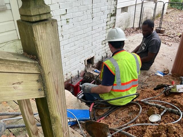 Foundation Crew Stabilizing Chimney Through Patio Access