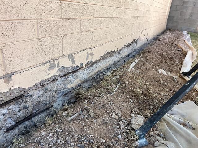 Flaking paint exposes two rusted rebars - stem wall foundation