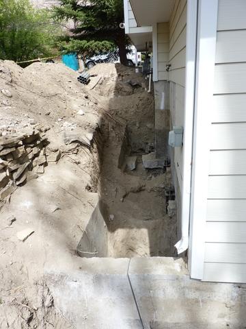 In this photo you can see the abandoned foundation as it extended from the active foundation of the home. You can see the angled relief cut made in the stem wall and the cut thru the center support footing. The FSI Model 288 resistance piers have been installed.