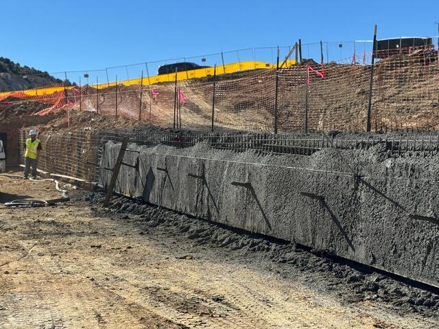 The owner torques the soil nail bearing plates into position as part of the wall stabilization system. These plates secure each nail against the shotcrete wall, ensuring proper tension and structural performance across the soil nail grid.