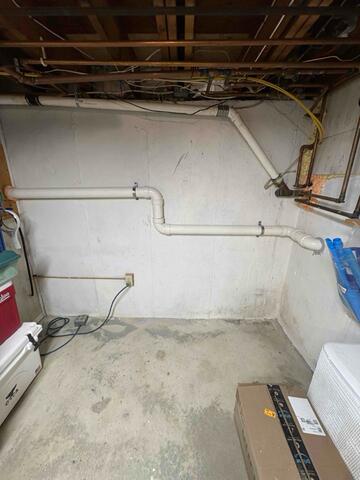 Completed Radon Mitigation Pipe Installation Along Basement Wall
