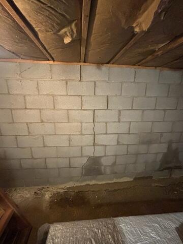 The vertical cracks and bowing wall of the cellar show just how severe the damage was becoming. This movement indicated there was significant structural stress from outside pressure and water intrusion, needing immediate stabilization.