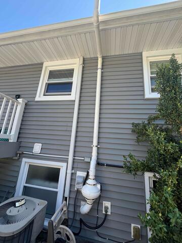 Completed exterior radon piping routed from the home toward the rear.