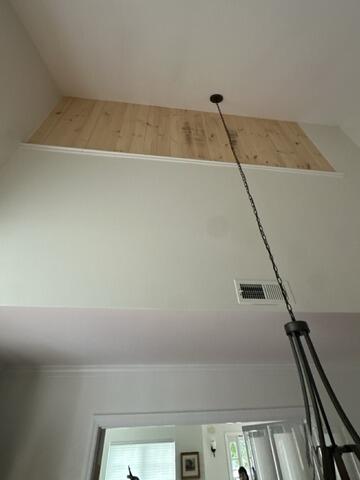 High-ceiling foyer view showing completed custom wood paneled wall cutout enclosure.