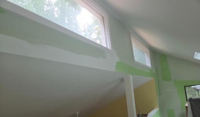 Meticulous wall masking and edge cutting around high-reach interior windows prior to painting