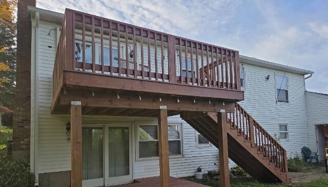Fully refinished two-story deck with a rich, protective wood stain on upper levels, lower patio decking, and exterior stairs