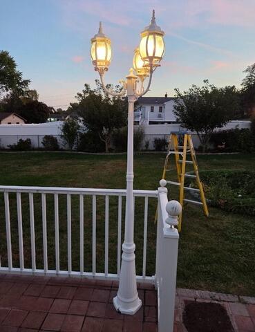 After: Fully restored and freshly painted white post light illuminating the garden.