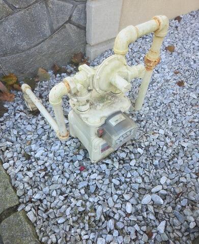 Weather-damaged gas meter exhibiting surface rust and peeling paint prior to treatment.