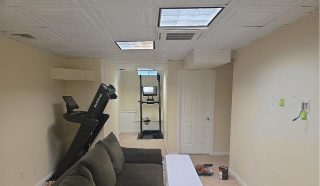 After: Freshly painted blue basement lounge and workout area featuring clean white trim