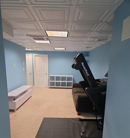 After: Freshly painted blue basement lounge and workout area featuring clean white trim.