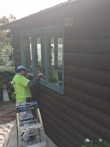 Precision detail work painting light-blue accent trim around lower-level window frames.