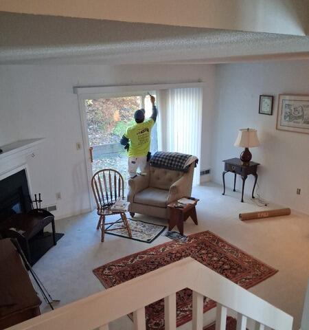 Professional interior painter meticulously prepping and coating trim and high-reach wall areas in a spacious Shelton, CT living room