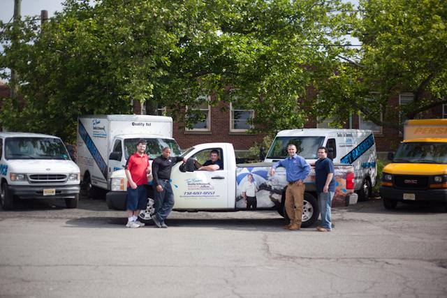 The Service Team stands in front of our fleet of service vehicles