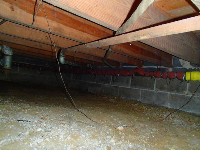 <p>This crawl space has absolutely no protection and no barriers from the outside elements. The floor, walls, and ceiling are completely exposed. This can result in flooding and ultimately damage to the wooden framing of your home. We recommend crawl space encapsulation to protect against moisture damage and provide the much needed barrier.</p>