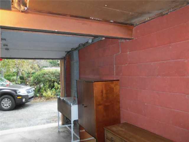 A crack like this is a sign of foundation settlement, as the wall bulges or "bows" from uneven pressure on it - in this case, the pressure from the retaining wall, which shifted as a result of pressure from the porch.