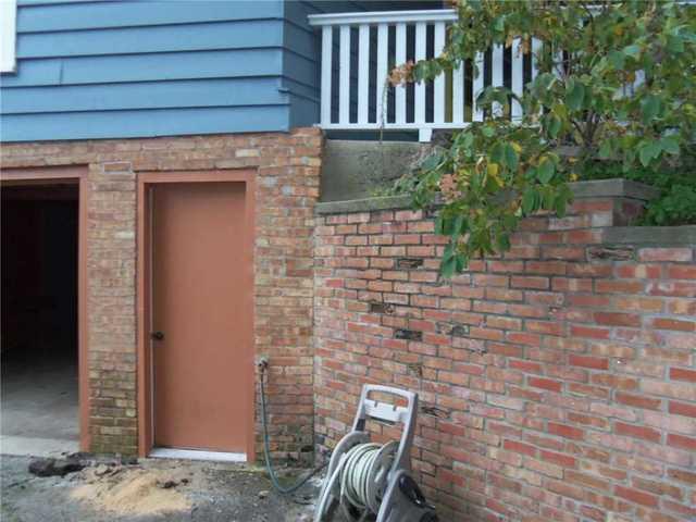 It's difficult to show all of the effects of this sinking foundation at once, but let's try. The foundation slab below the porch is settling, which caused the porch to tilt. This caused the support beam for the roof to slip off-kilter. The newly distributed weight from the porch put pressure on the retaining wall, which in turn put pressure on the garage wall, which cracked and bowed.

Phew.