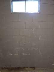 Note the efflorescence - aka the white powder - on the wall beneath the window. Efflorescence occurs when water travels through concrete blocks, dissolving minerals present and bringing them to the surface. When the water evaporates, the mineral deposits are left behind. This sign of water issues is usually just a nuisance, but over time it can degrade the blocks.