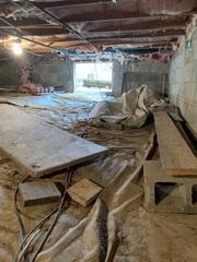 Typical dated crawlspace with old vapor barrier and debris.