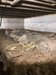 In this photo, we see the initial state of the crawl space. It is cluttered, with exposed dirt, debris, and signs of moisture damage. The space feels damp and unwelcoming, posing a potential threat to the overall integrity of the home.