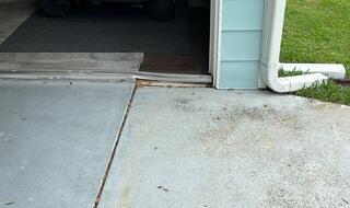 Soil settlement has caused the concrete slab to sink, creating an uneven surface.