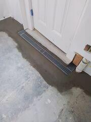 TrenchDrain resembles half of a basement drainage pipe, with a grated opening fitted snugly on top. The grate is flush or slightly below the floor, eliminating any tripping hazard.