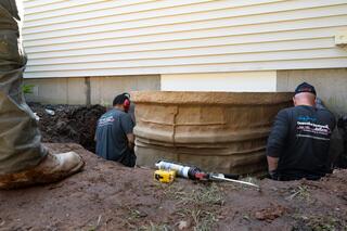 Fastening the Rockwell window well to the concrete foundation provides further stability, making the window well plumb.