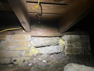 The original block piers in the crawl space, which had been supporting the home's floor joists, had deteriorated, resulting in sagging and instability in the floor joists.