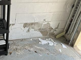 Water intrusion had caused efflorescence to form along the interior walls of the homeowner's garage.