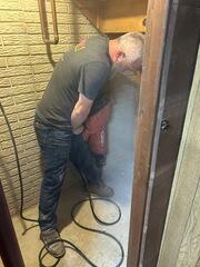 Dan jackhammers a small area for any water to be drained through the FlexiSpan drainage channel.