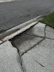 The section of concrete at the end of the homeowner's driveway had sunken significantly, creating a serious tripping hazard and causing damage to their vehicle.