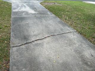 Soil settlement beneath the driveway caused the concrete slabs to shift, resulting in large cracks throughout the surface.