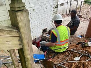 Foundation Crew Stabilizing Chimney Through Patio Access