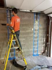 Bryce carefully installs CarbonArmor® straps to reinforce the foundation wall, adding strength and preventing further inward movement.