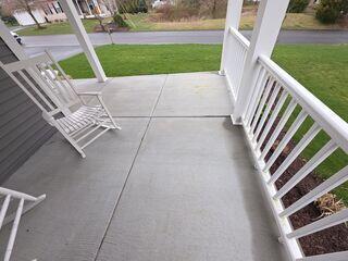 The porch has begun exhibiting early signs of structural settlement, evidenced by differential displacement between adjacent concrete slabs at the expansion joints. Additionally, the deck is gradually subsiding, forming a concave or 'bowl-shaped' depression indicative of uneven support or soil movement beneath the structure.