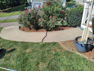 The walkway leading to the home's main entrance exhibited a significant structural fracture, presenting a substantial tripping hazard. This damage was primarily caused by void formation beneath the concrete slab, which compromised its ability to distribute load effectively. As a result, differential settlement occurred, with one section of the slab subsiding beneath the adjacent portion, indicating a loss of subgrade support and potential soil instability.