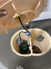 The new SingleSafe™ sump pump is carefully placed inside its liner, ready to provide reliable basement drainage and protection against water intrusion.