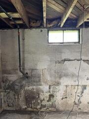 One wall in this basement began to bow outward from pressure. As the wall bowed out, cracks began to form, and water started to leak through them and into the basement.