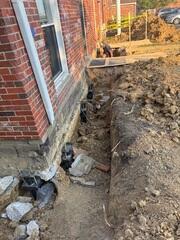 To install our helical piers into stable, load-bearing soil, we first expose the home's footing. Once the piers are drilled down, we secure them to the underside of the footing using our "L"-shaped brackets, which latch firmly beneath the foundation for a strong, permanent connection.