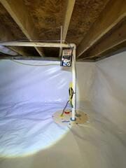 The newly installed sump pump system efficiently collects and discharges water, keeping the crawl space dry year-round.