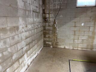 The cinder block walls of this basement show signs of moisture.