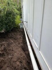 The French drain system is installed around the exterior of the property, near the foundation. It is designed to redirect water away from the structure to prevent water intrusion and protect the foundation from damage.