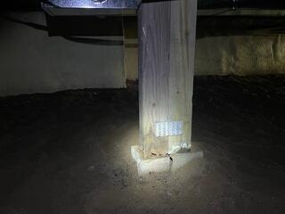 The original wooden post shows clear deterioration and inadequate footing support, a common cause of floor sagging and structural instability.