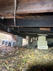 During the crawl space inspection, many of the wooden floor joists were found to be sagging due to inadequate support from below. Temporary fixes, including stacked cinder blocks, had previously been used in an attempt to provide supplemental support.