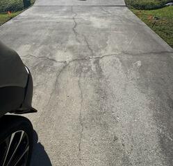 Cracks gradually appeared and worsened over time in the homeowner's concrete driveway as the underlying soil settled and eroded.